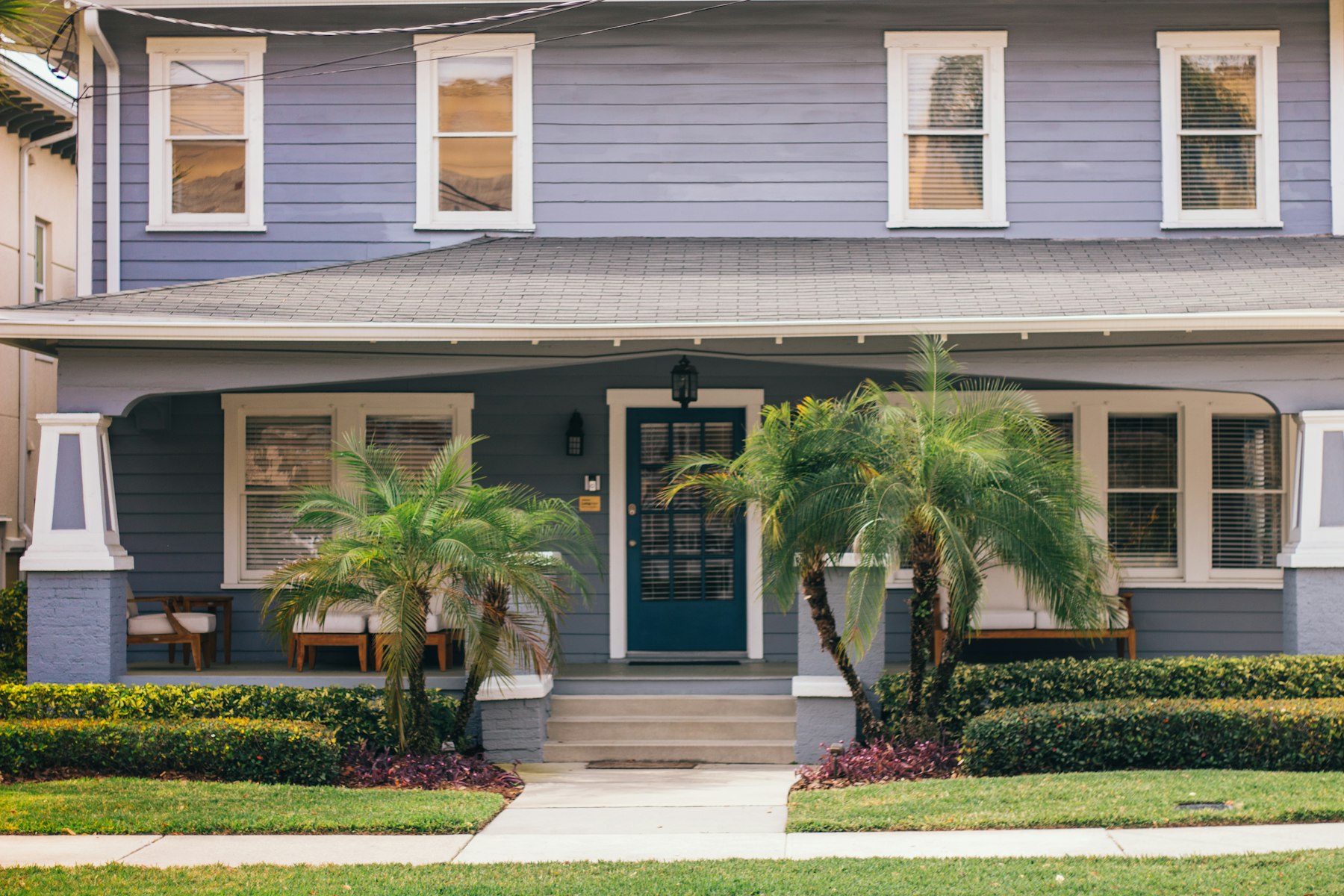 Blue Florida craftsman home with palms by the front porch