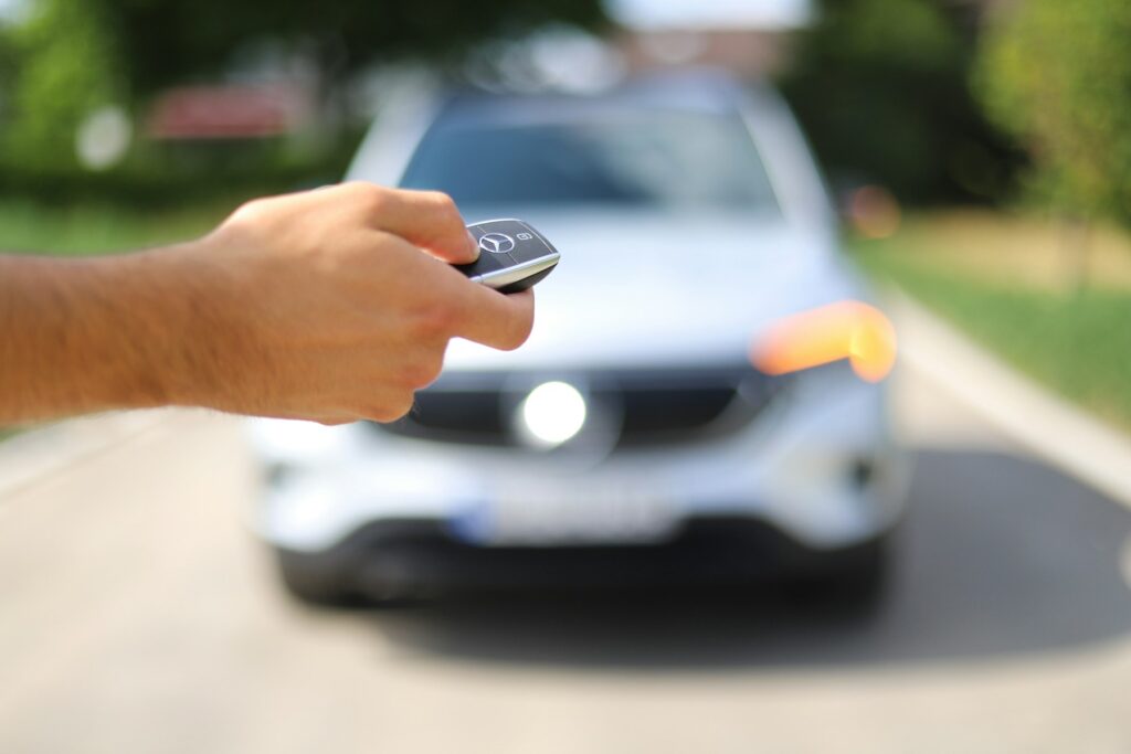 Driver pointing a key fob at a car